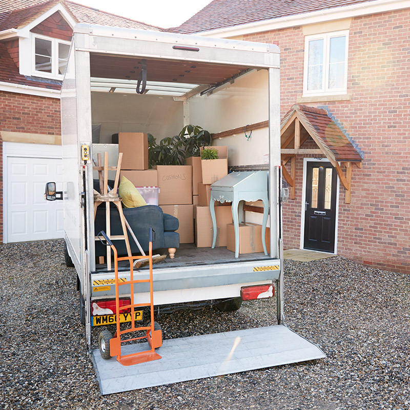 Removal Truck Waiting To Be Unloaded Outside New Home On Moving Day